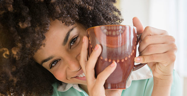Jeune femme souriante buvant une tasse de boisson chaude RICORÉ®-