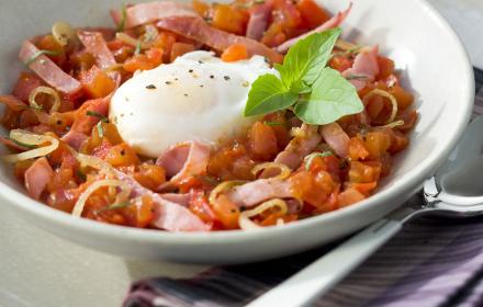 Oeufs poches sur lit de tomates au bacon